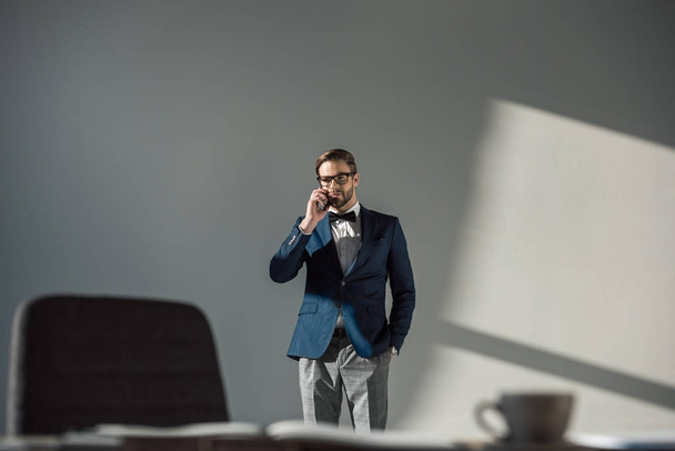 selective focus of man in eyeglasses and bow tie talking by smartphone   - Foto, afbeelding