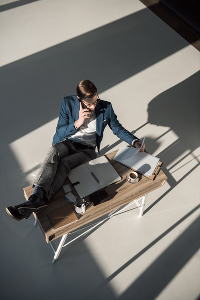vista ad alto angolo di uomo d'affari che parla su smartphone mentre si siede sul posto di lavoro
  - Foto, immagini