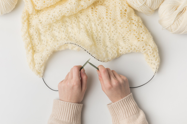 vista recortada de la mujer tejiendo lana blanca con agujas sobre fondo blanco
 - Foto, Imagen