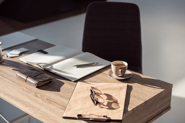 close-up view of eyeglasses on clipboard, cup of coffee and office supplies at workplace  - Foto, imagen