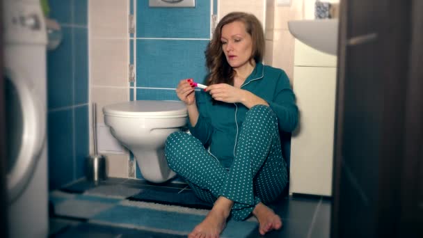 Dühös fiatal nő pizsamában dobja a terhességi teszt és kötött szekrényből fürdőszoba - Felvétel, videó