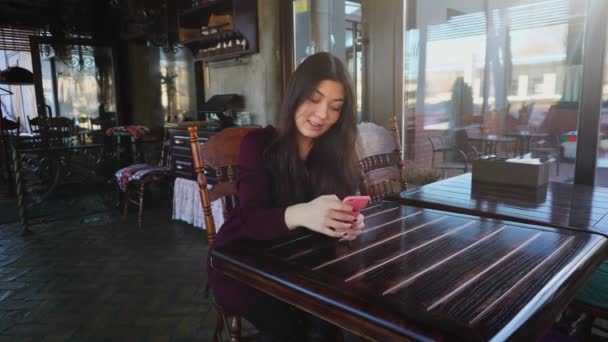 Fiatal nő tanár ellenőrző vizsgálatok kávézóban használ smartphone. - Felvétel, videó