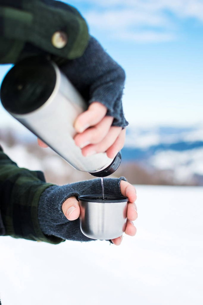 Mann benutzt Thermosflasche an einem Wintertag - Foto, Bild