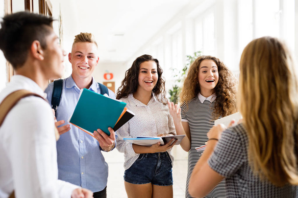 Teenage students walking in high school hall, talking. - Photo, image