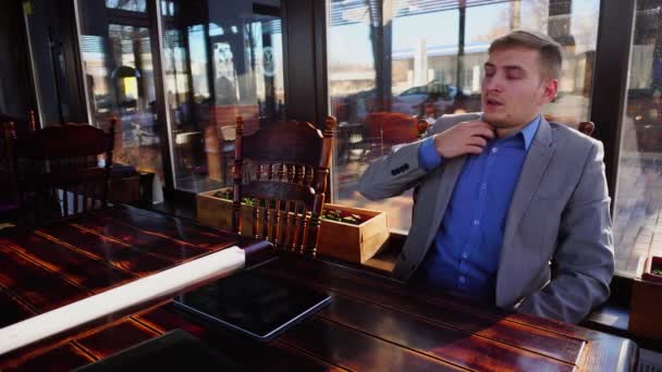 Uitgeput man rusten in café en het gebruik van Tablet PC in de buurt van roletui van papier en documenten. - Video