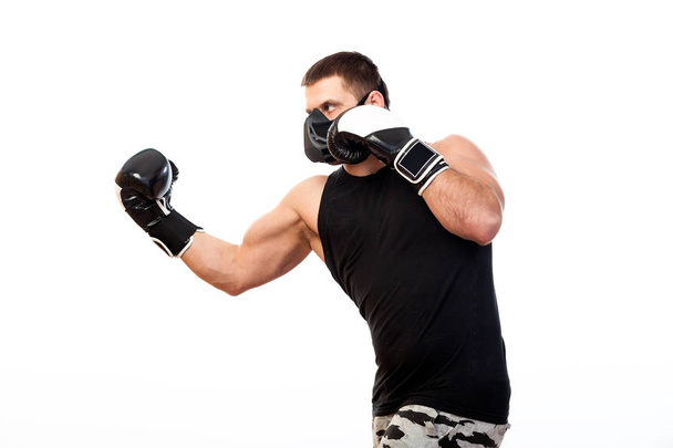 Atleta masculino forte em uma máscara de treinamento preto, camisa de esportes e caixa de luvas de boxe em um fundo isolado branco
 - Foto, Imagem