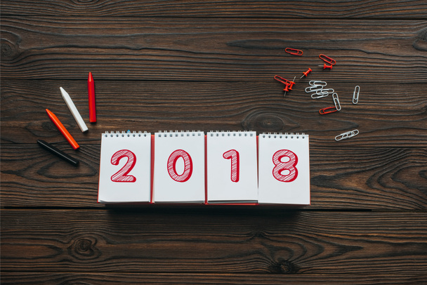 top view of 2018 calendar, pencils and stationery on wooden tabletop - Fotoğraf, Görsel