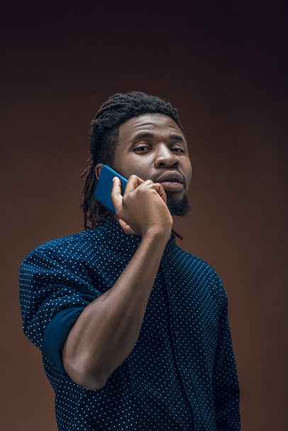 african american man talking by smartphone isolated on brown - Fotoğraf, Görsel