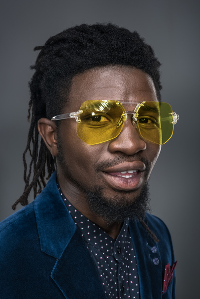 portrait of handsome african american man in yellow sunglasses isolated on gray - Foto, Bild