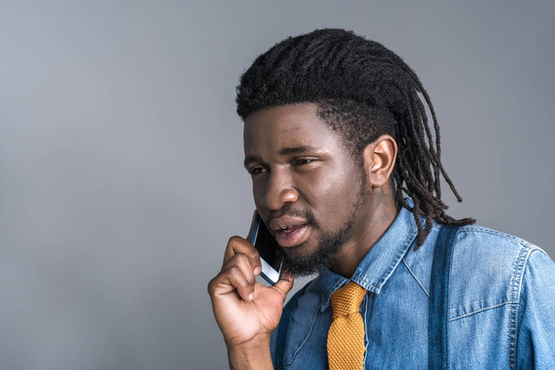 stílusos afro-amerikai ember beszél a smartphone elszigetelt szürke - Fotó, kép