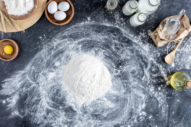 flat lay with flour and other ingredients for bakery, kitchenware on dark tabletop - Photo, Image