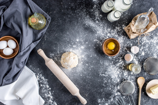 top view of raw dough, baking ingredients and cutlery on marble surface - Foto, afbeelding