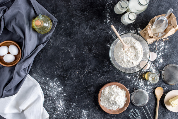vista superior de utensilios de cocina arreglados e ingredientes para hornear pan en la superficie de mármol oscuro
 - Foto, imagen