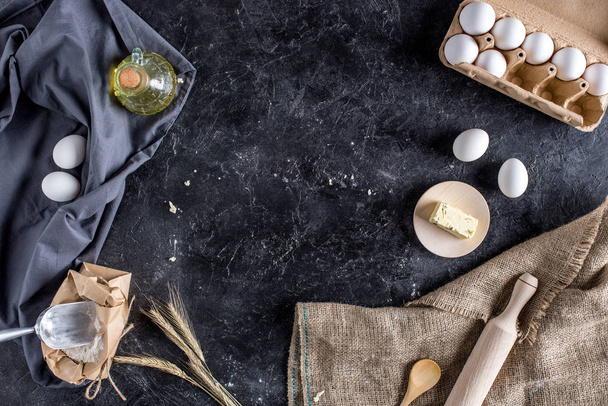 flat lay with various ingredients for bread baking and cutlery on dark marble surface - Fotó, kép