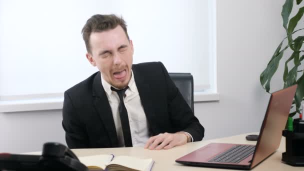 Young businessman in suit sitting in office and Sticks Tongue Out, Makes Funny Faces 60 fps - Video, Çekim