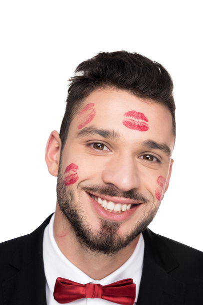 lächelnder gutaussehender Mann mit Lippenspuren im Gesicht, der in die Kamera schaut, isoliert auf Weiß - Foto, Bild