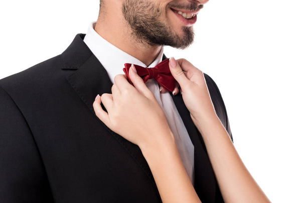 cropped image of girlfriend fixing boyfriends tie bow isolated on white - Foto, afbeelding