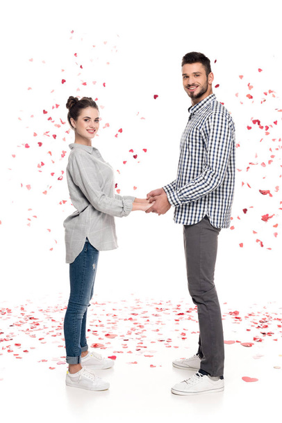 para, trzymając się za ręce pod spadające konfetti na biały, koncepcja Walentynki - Zdjęcie, obraz