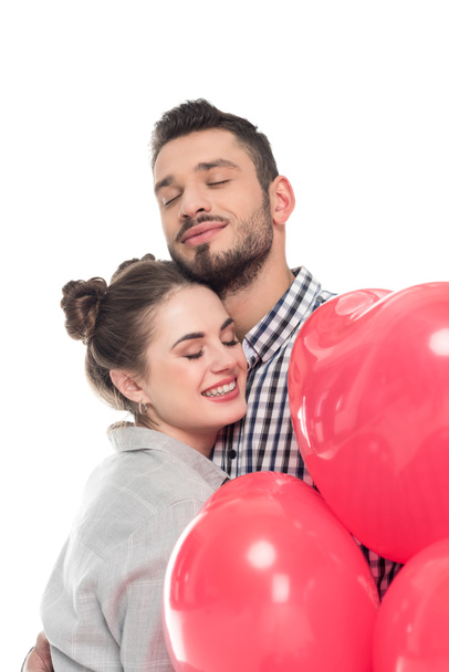 couple hugging and holding heart shaped balloons isolated on white, valentines day concept - Фото, изображение