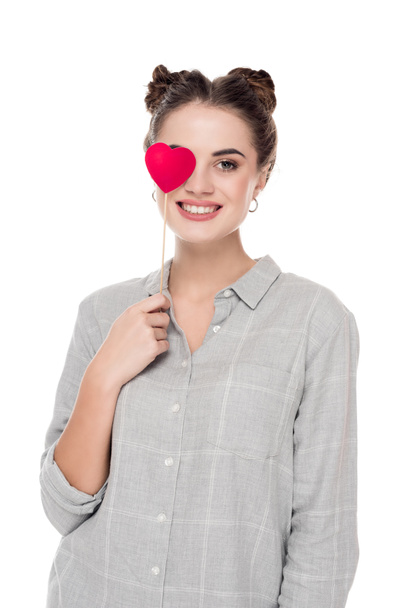 smiling girl covering eye with paper heart isolated on white, valentines day concept  - Fotografie, Obrázek