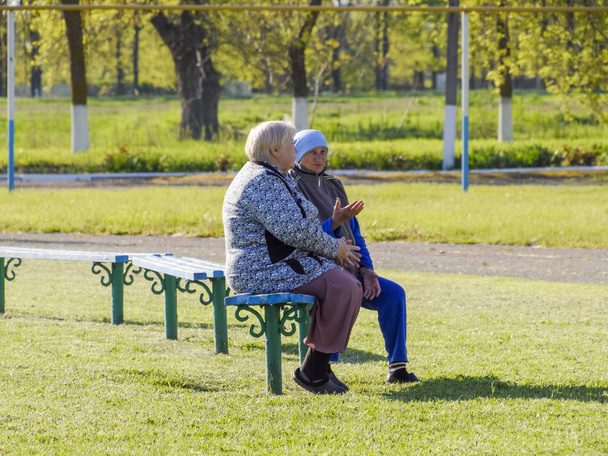 Two elderly retired women sit on a bench and discuss their lives. Life is retired. The aged people. - Photo, Image