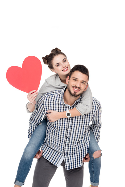 boyfriend giving piggyback to girlfriend holding red heart isolated on white, valentines day concept - Fotoğraf, Görsel