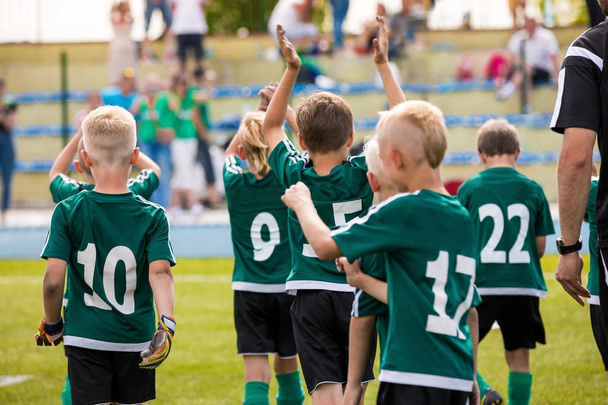 子供たちはサッカーの勝利を祝っています。少年サッカーの試合を記念に勝ちます。決勝戦の後の幸せなサッカー選手のグループ。少年サッカー サッカー選手権を祝う - 写真・画像