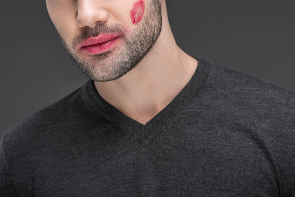 cropped view of man with kiss print on cheek, isolated on grey - Foto, imagen