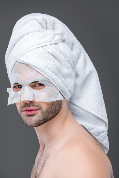 pohledný muž s ručníkem a kolagen maska, izolované Grey, koncept péče o pleť - Fotografie, Obrázek