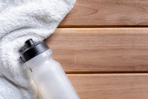 weißes Tuch und Wasserflasche aus Kunststoff auf Holztisch  - Foto, Bild