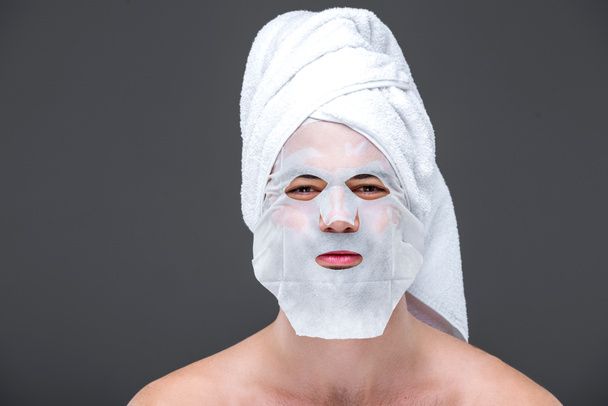 homem bonito com toalha e máscara de colágeno, isolado em cinza, conceito de cuidados com a pele
 - Foto, Imagem