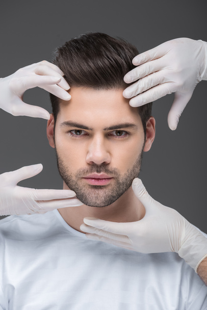 handsome man and doctors hands, isolated on grey, skin care concept - Photo, Image