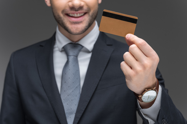 cropped view of businessman holding golden credit card, isolated on grey - Photo, Image