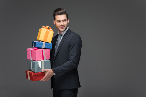 bearded man holding gift boxes, isolated on grey - Foto, Imagen