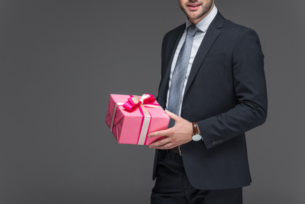 cropped view of man in suit holding present, isolated on grey - Foto, Imagen