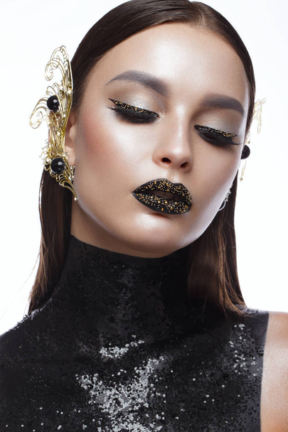 Beautiful girl with black creative art make-up and gold accessories. Beauty face. - Foto, Imagem