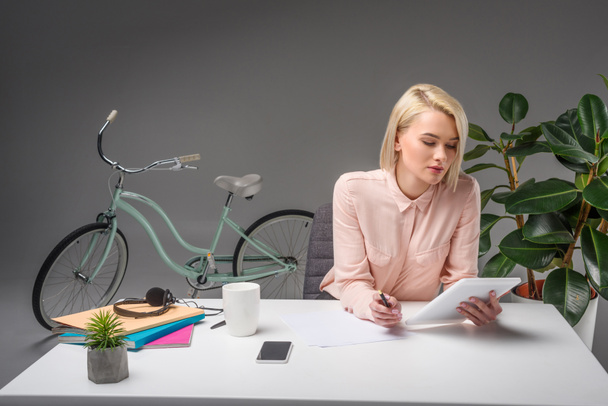 beautiful young businesswoman using tablet at workplace isolated on grey - Photo, image