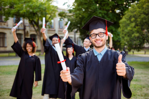 Happy caucasian male grad is showing good sign, blurred class ma - Photo, Image