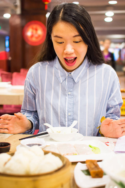 Mujer asiática disfrutando de la comida china en restaurante chino
 - Foto, Imagen