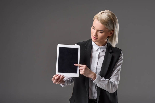 portrait of beautiful young woman pointing at tablet with blank screen isolated on grey - Foto, Imagem