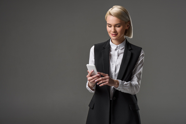 portrait of attractive woman using smartphone isolated on grey - Fotografie, Obrázek