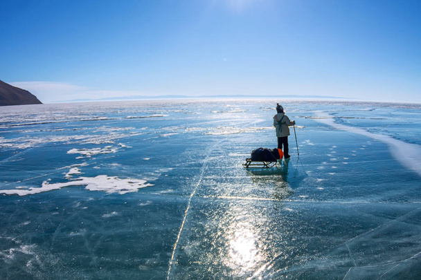 child girl with a sledge and trekking pole is on the ice of Lake Baikal. - Valokuva, kuva