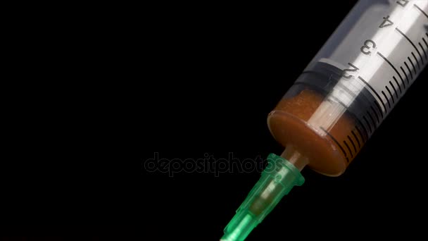 Spritze mit Blut auf schwarzem Hintergrund in Großaufnahme. die Spritze mit dem Medikament ist injektionsfertig. Medizinische Spritze gefüllt mit roter Flüssigkeit. - Filmmaterial, Video