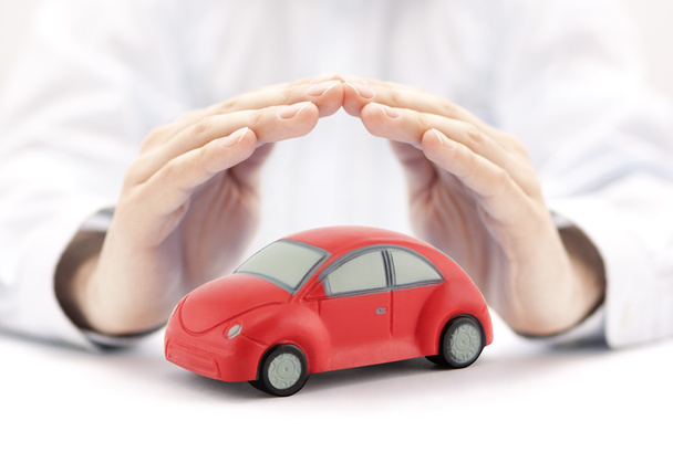 Concepto de seguro de coche. Coche de juguete rojo cubierto por manos
 - Foto, imagen
