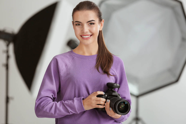 Beautiful young photographer with camera in professional studio - Φωτογραφία, εικόνα