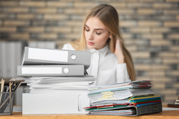 Young woman with stack of documents on her table in office - Photo, Image