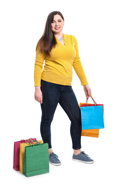 Beautiful overweight woman with shopping bags on white background - Photo, image