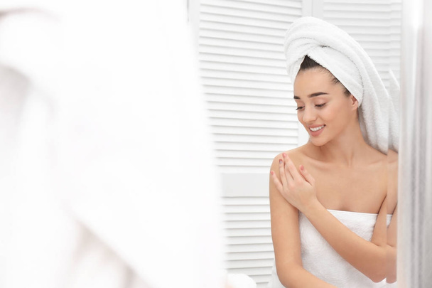 Young woman in white towel using cosmetic product at home - Фото, изображение
