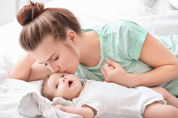 Молодая мать и симпатичный ребенок на кровати дома
 - Фото, изображение