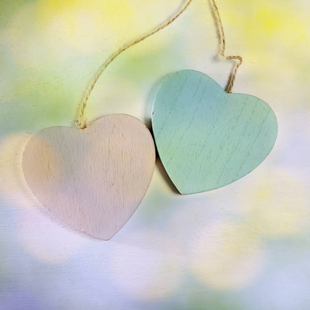 Two wooden hearts hang on a white wooden wall - Foto, imagen